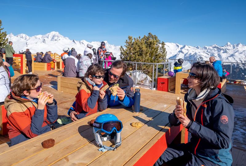 A family sits outside having a picnic in a high alpine restaurant terrace