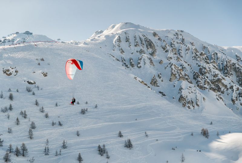 A parapente flies above the snow