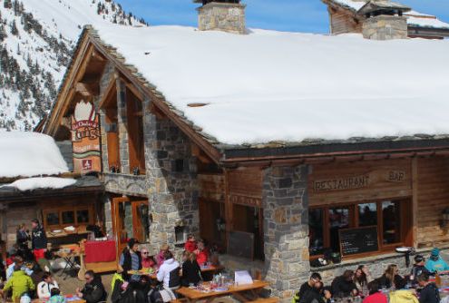 An alpine lodge terrace is photographed with people sat outside eating