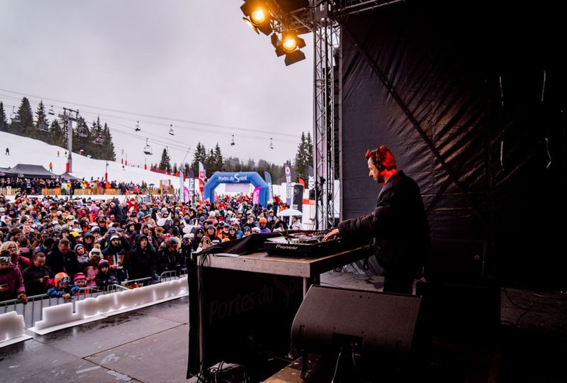 an outdoor winter alpine music festival shot from the stage, to both the DJ nd the crowd