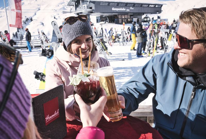 drinks are cheersed around a table, in front of a chairlift area