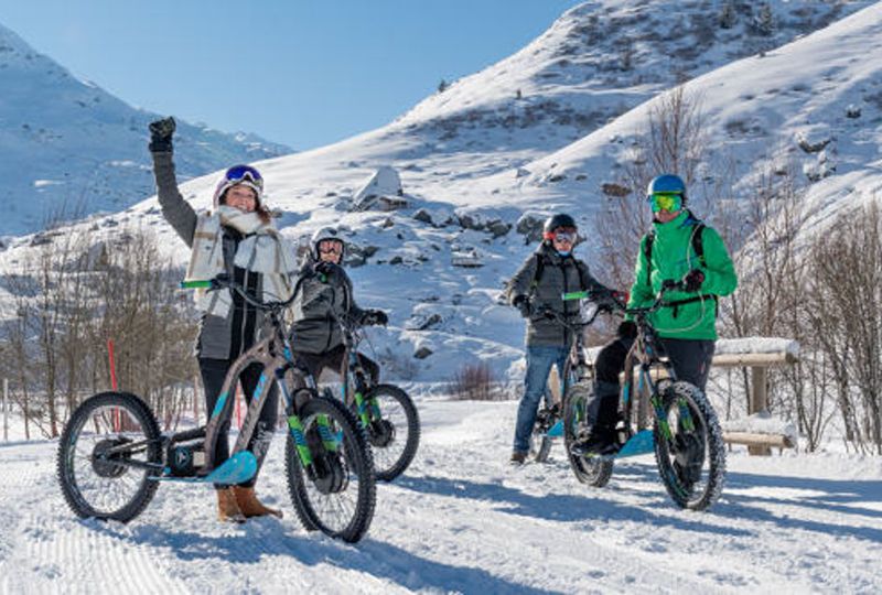 fat bikers stand on snow, smiling at camera, in a snowy setting