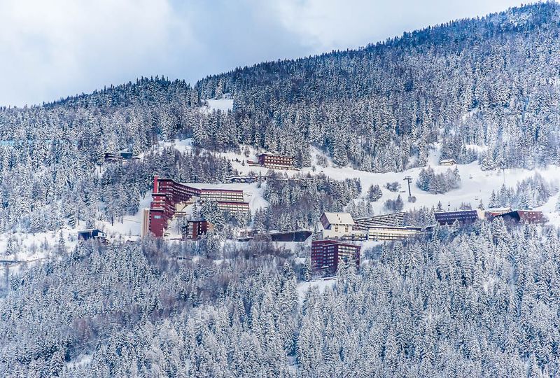 A drone shot of the snowy alpine village of Les Arcs on a hill