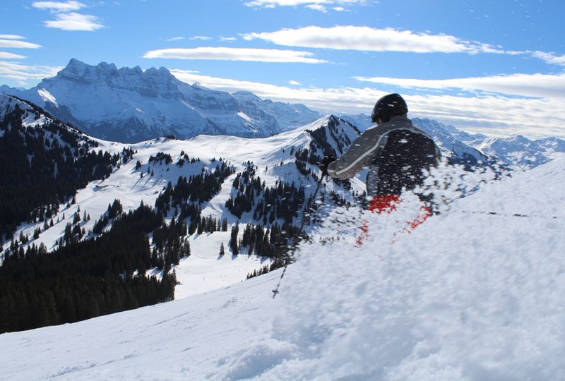A skier sprays slushy snow off-piste skiing