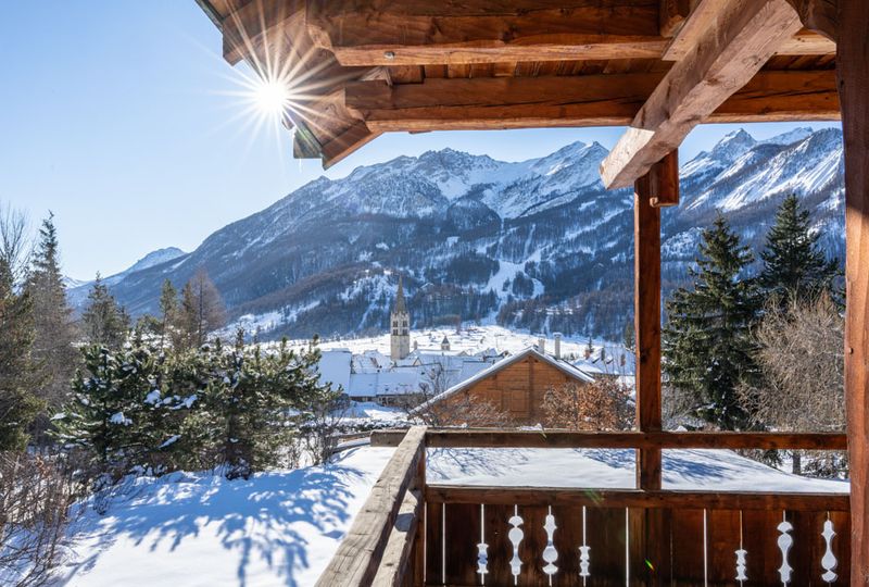 A wooden chalet balcony surrounded by snow