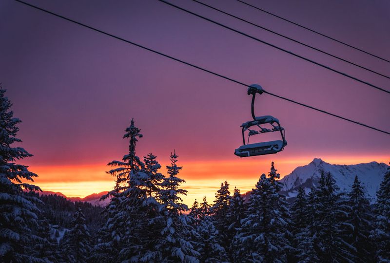 purple-orange-yellow sunset colours the sky, with a chairlift in foreground